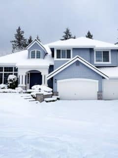 large gray house in winter with snow on the ground