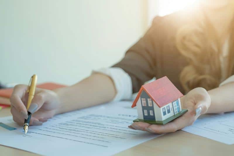 holding model of house while signing contract