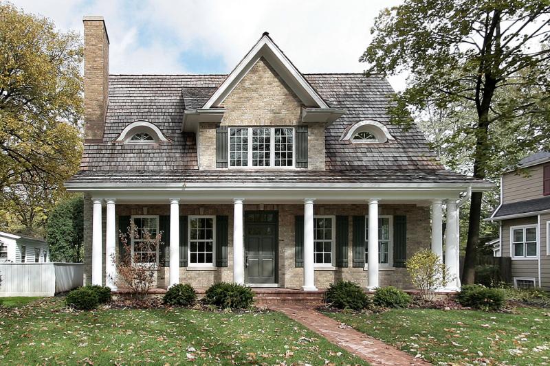 house with shingled roof surrounded by trees and other houses