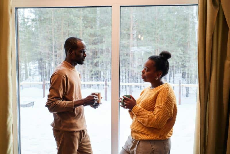 black couple talking in front of windows