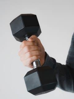 man's hand lifting a black dumbbell