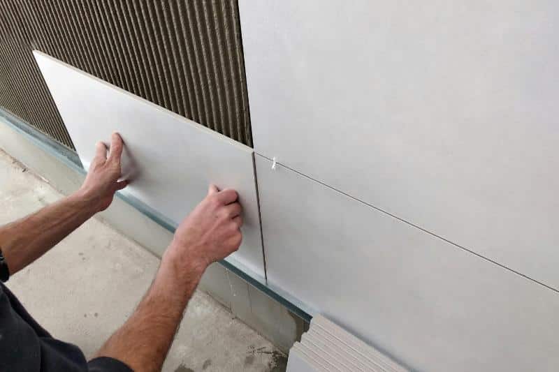 man installing tile on wall