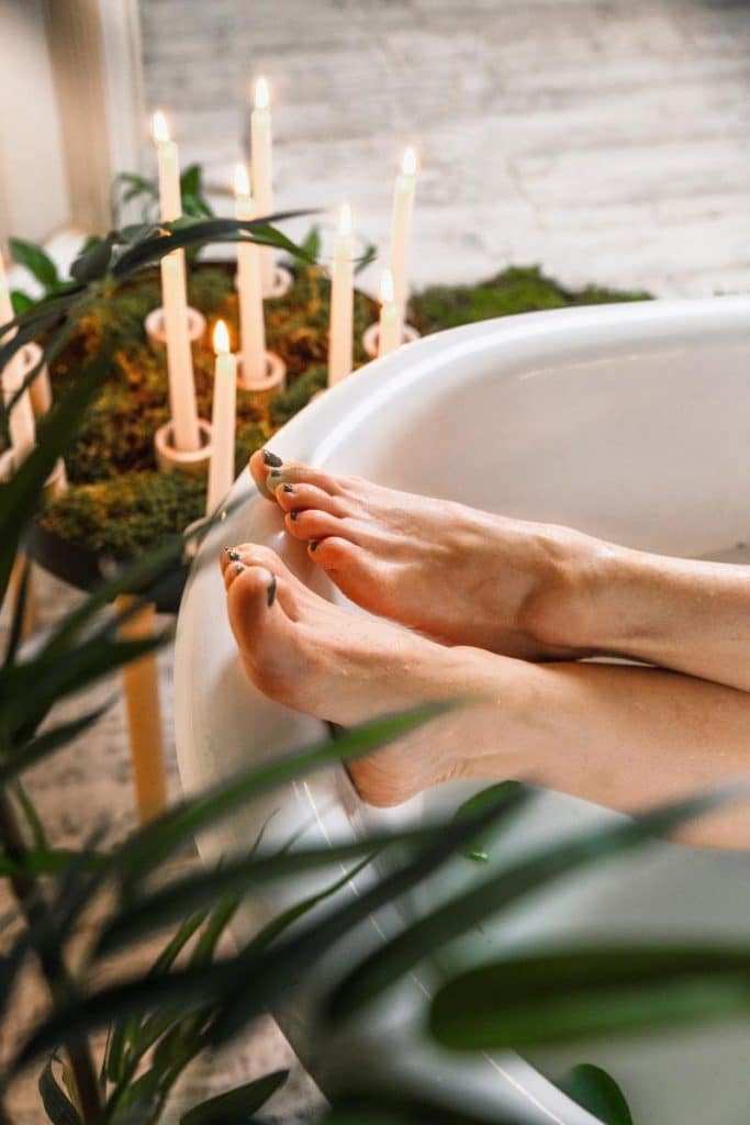 plants and candles surrounding a bathtub