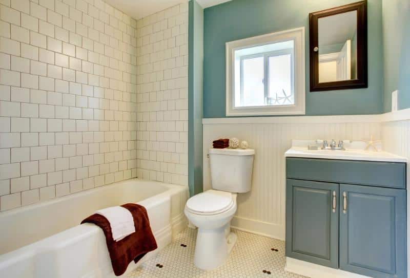 remodeled bathroom with teal cabinet and accent wall and white tiles