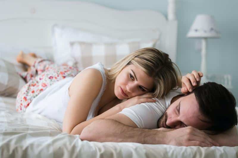 woman and man on bed looking sad