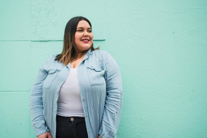 smiling plus size woman against light teal wall