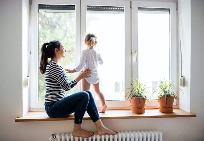 woman with feet on radiator and daughter in window