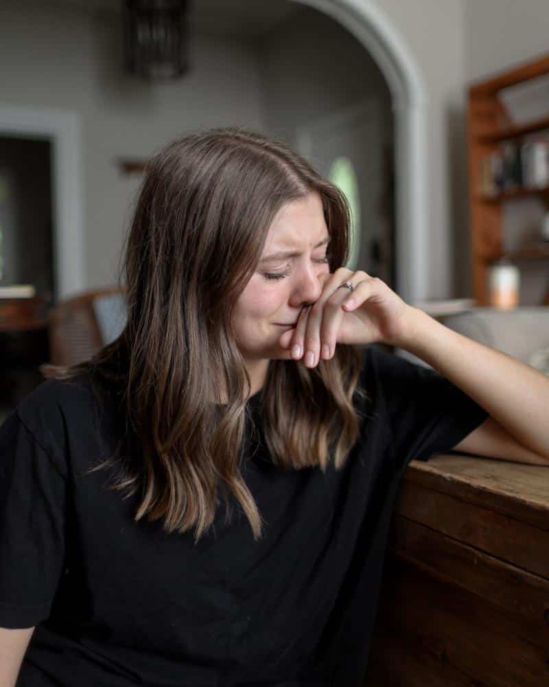 woman crying with face resting on hand