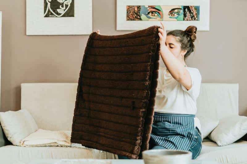 woman sitting on couch holding up fuzzy brown blanket