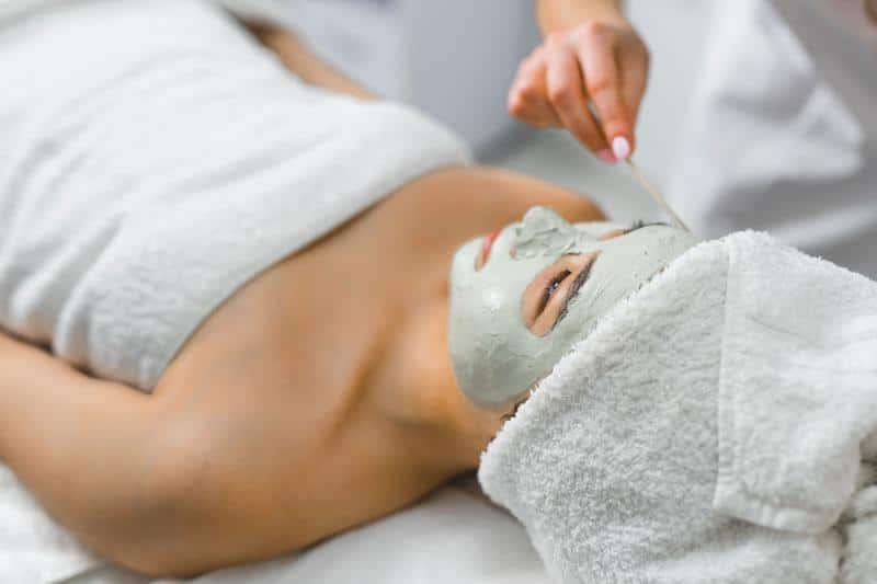 woman at spa in a towel with face mask being applied