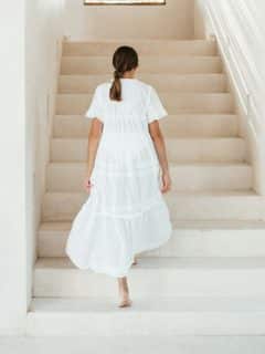 woman in white dress walking up white staircase