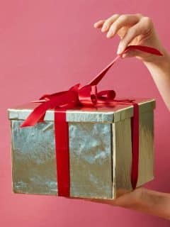 woman's hand pulling ribbon on gift box