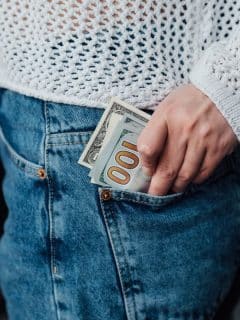 woman in mesh top and jeans putting money in pocket
