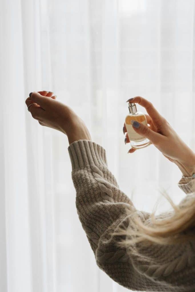 woman spraying perfume on wrist