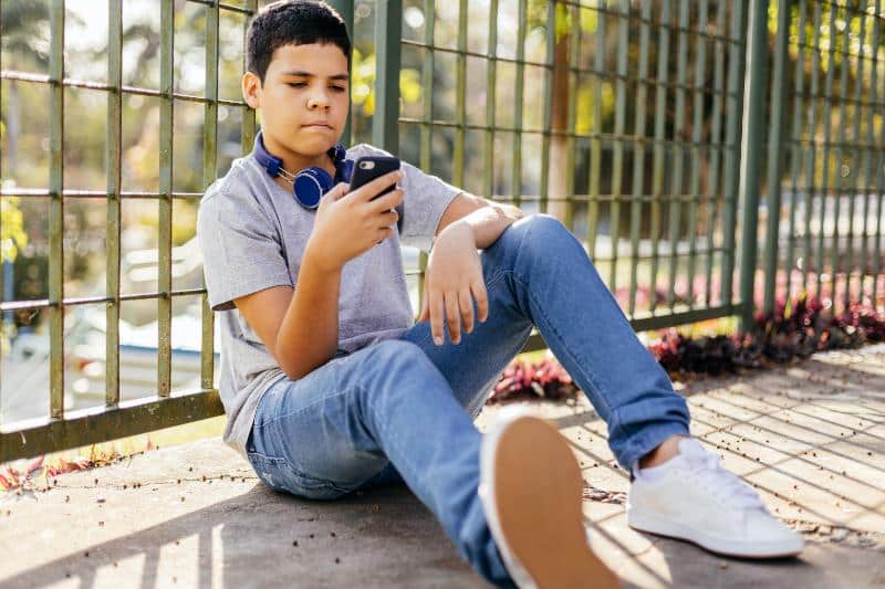 young preteen boy looking at smartphone outdoors