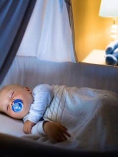 baby boy with pacifier sleeping in bassinet