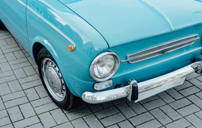 blue classic car on brick pavement