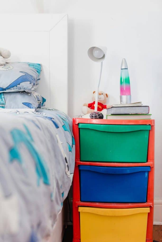 a child's bedroom with colorful storage beside bed