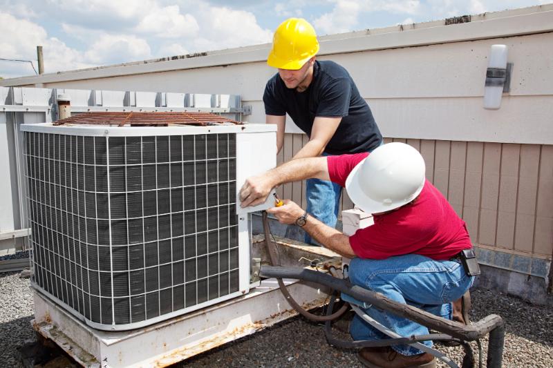 two men working on ac unit