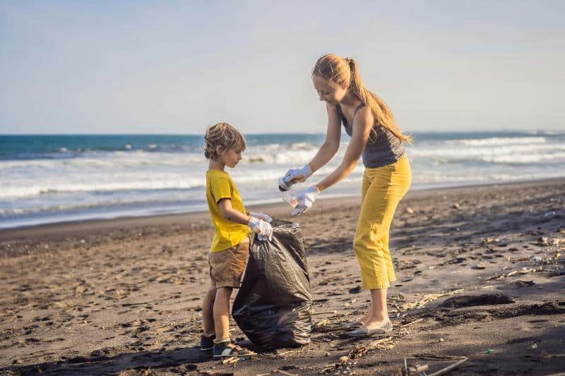 mother and son picking up trash at beach