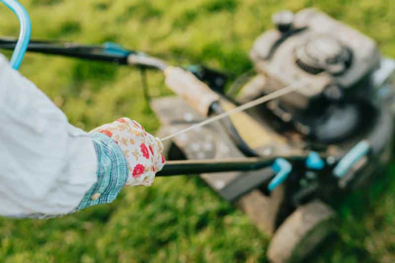 woman mowing the lawn wearing floral gardening gloves