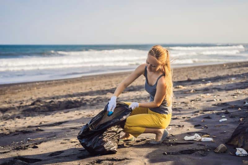 woman picking up trash on beach