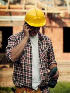 roofing worker on building site talking on mobile phone