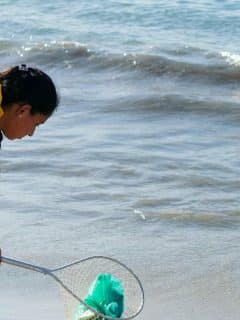 woman using net to get trash out of ocean