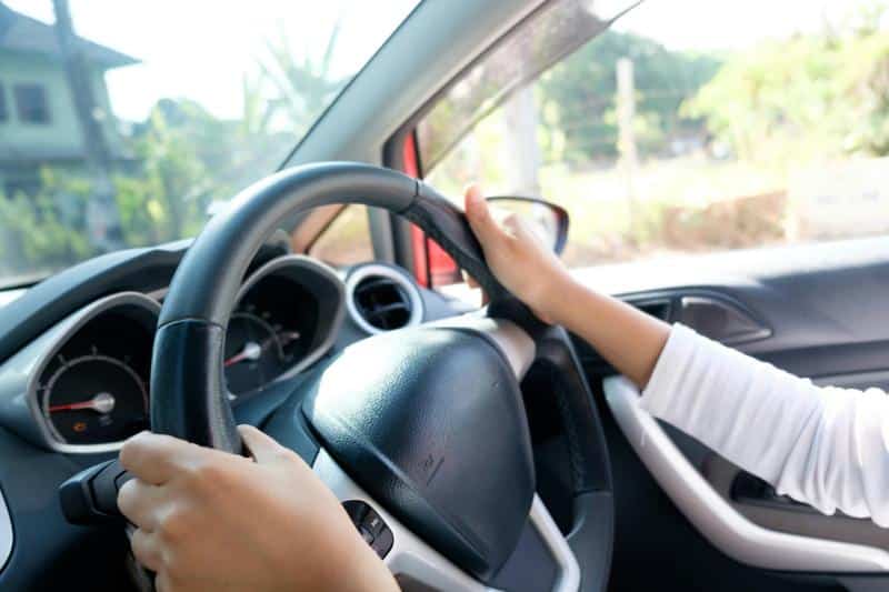 young woman with hands on steering wheel