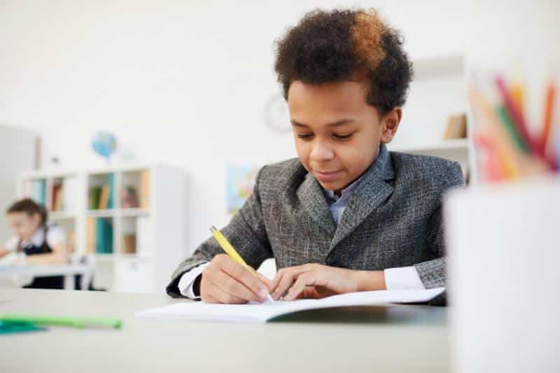 young boy taking notes in notebook