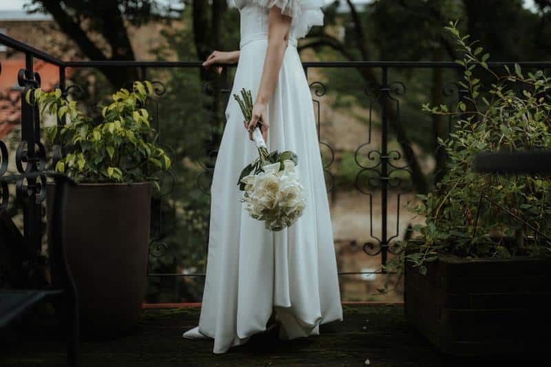 bride standing by iron fence with bouquet in hand