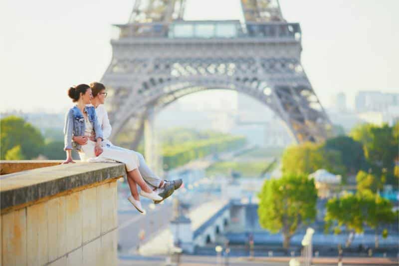 couple sitting on bridge near Eiffel Tower