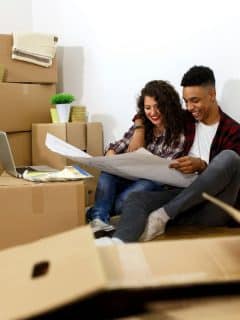 couple looking at blueprints and surrounded by boxes for moving