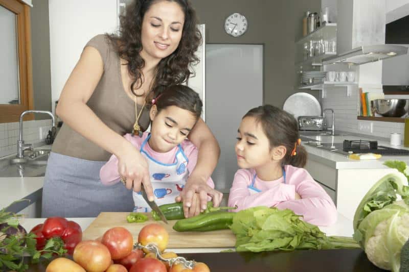 mom chopping vegetables with daughters