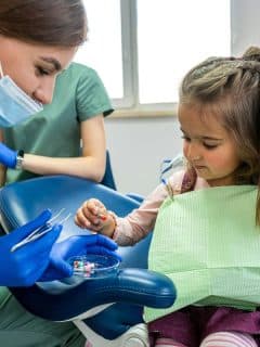 dentist showing little girl some dental accessories