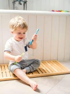 blonde toddler boy playing with toothbrushes