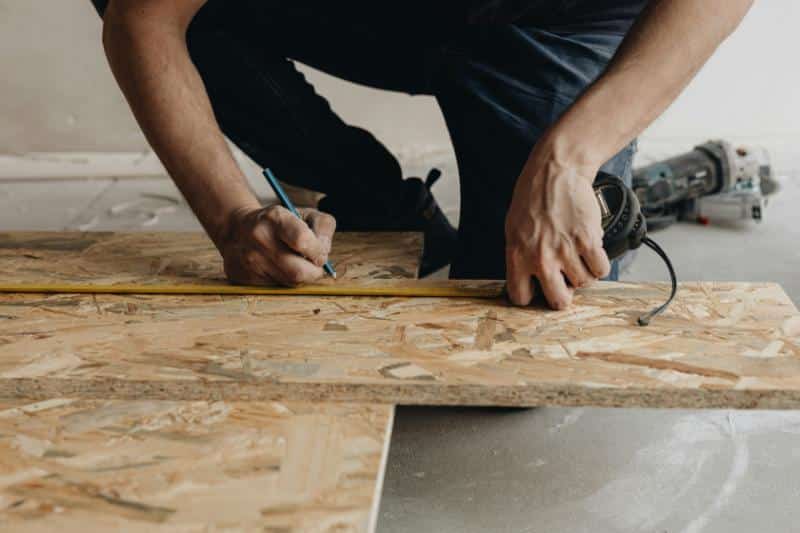 man measuring and marking a piece of plywood