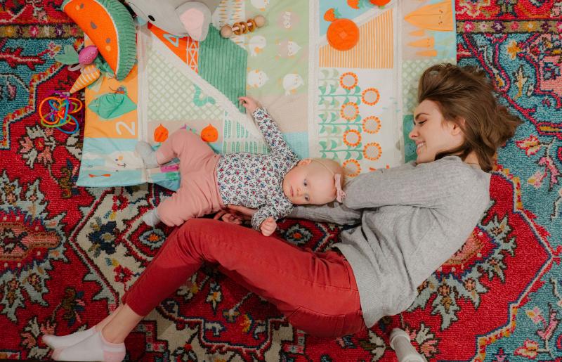 mom and baby girl on rug with baby on playmat