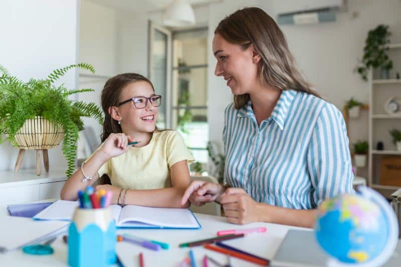 mother and daughter smiling at each other while homeschooling