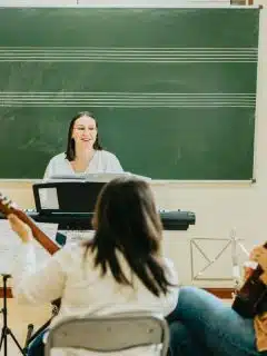 female music teacher in front with music stand directing students as they play instruments