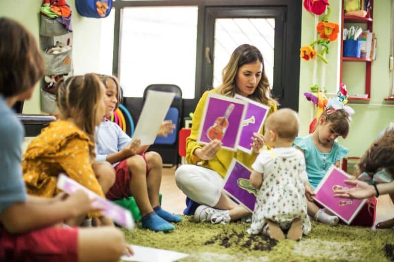 music teacher showing pictures of instruments to kids of various ages