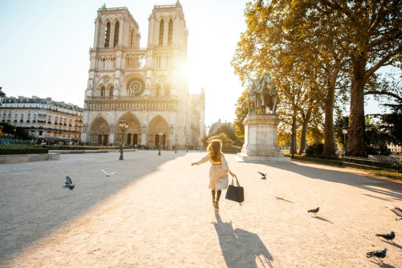 woman running through courtyard in front of Notre Dame Cathedral