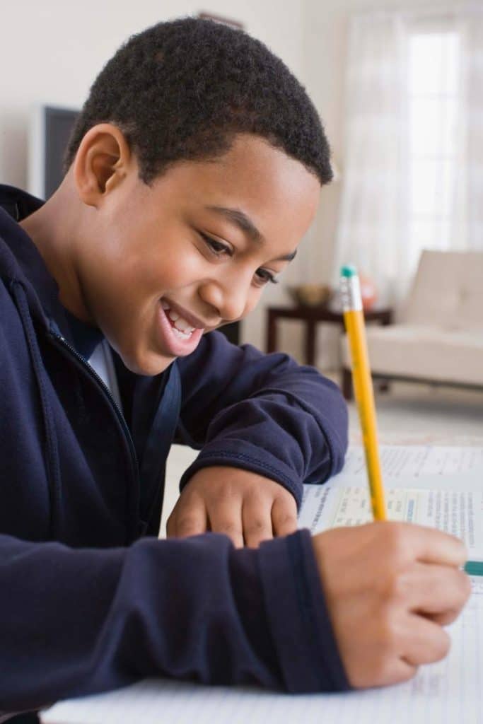 smiling boy writing with a pencil