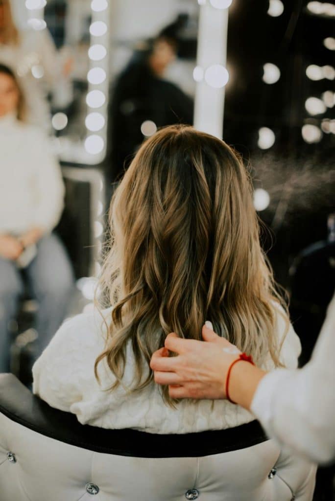 woman with blonde highlights getting her hair fixed by a stylist - waves can make your hair look thicker