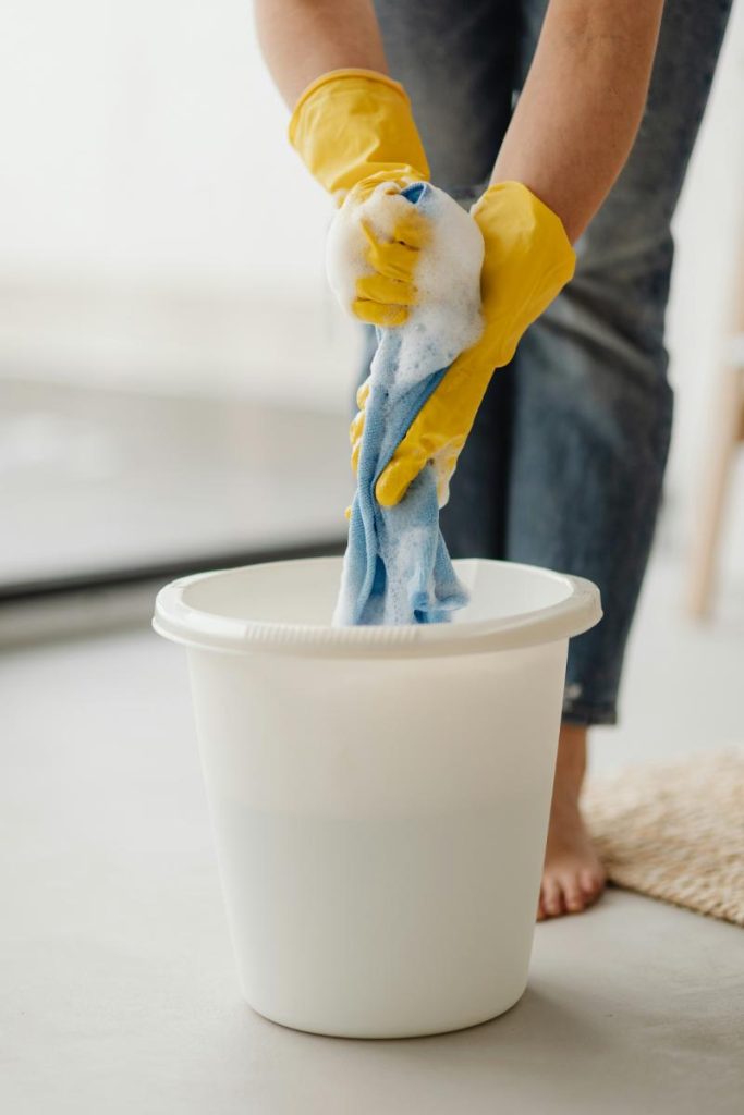 person wetting a cloth in a bucket