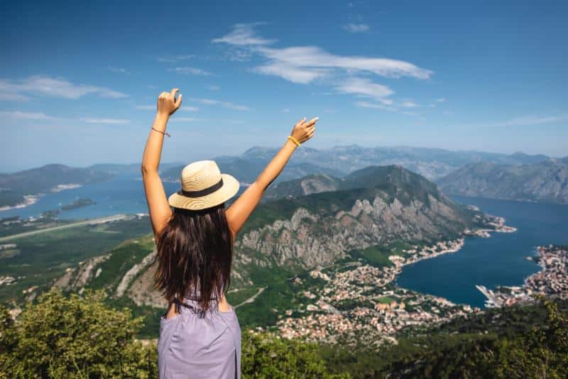 back view of woman with arms up overlooking Kotor in Montenegro