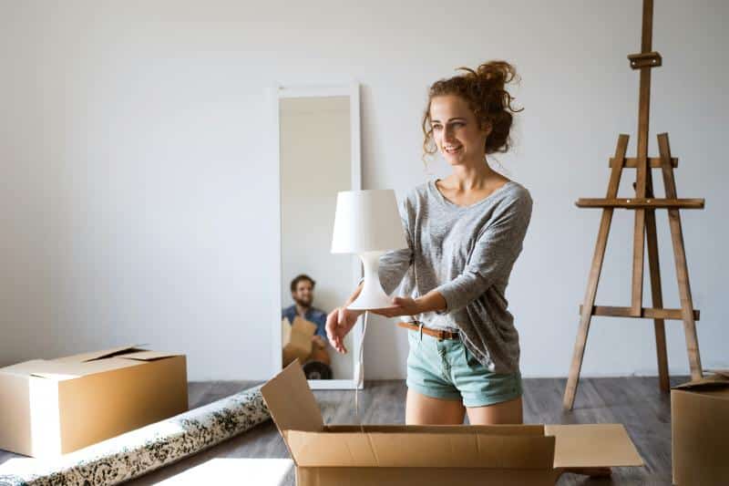woman packing a small lamp into a box for moving day