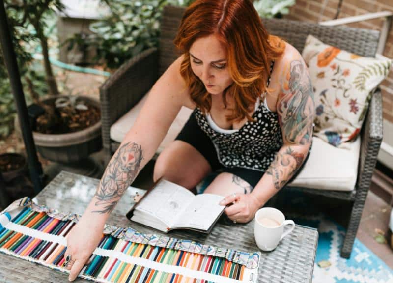 red-haired woman selecting a colored pencil to write in a journal