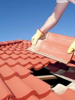 roofer repairing tiles on a roof