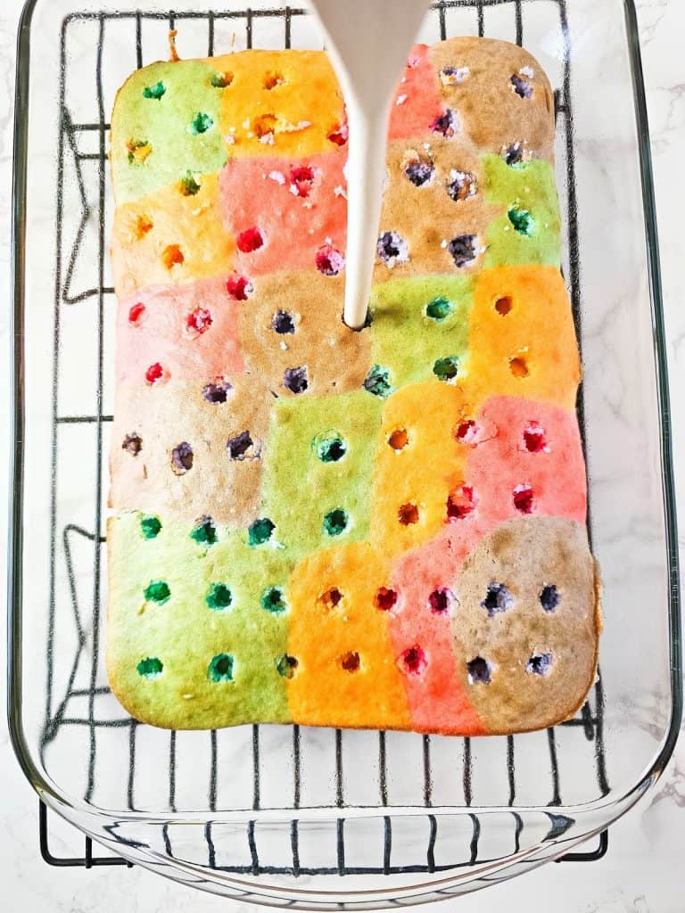 rainbow poke cake with holes poked in it